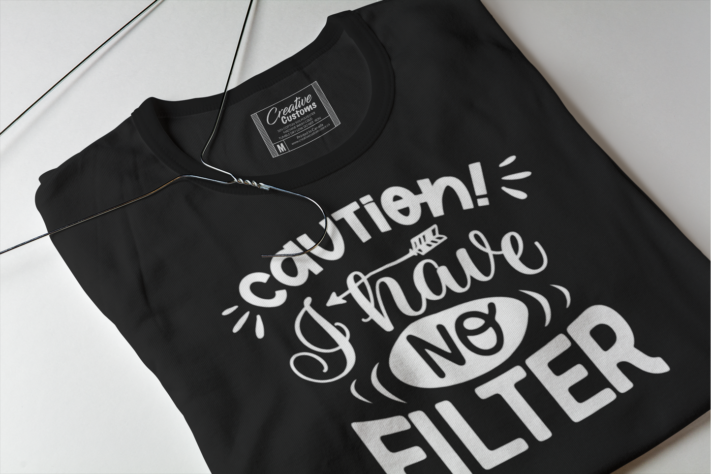 A black folded t shirt with white writing caution I have no filter