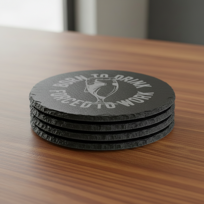 A round black coaster with a laser etched design featuring a tilted pint glass and the text 'BORN TO DRINK FORCED TO WORK' on a white background.