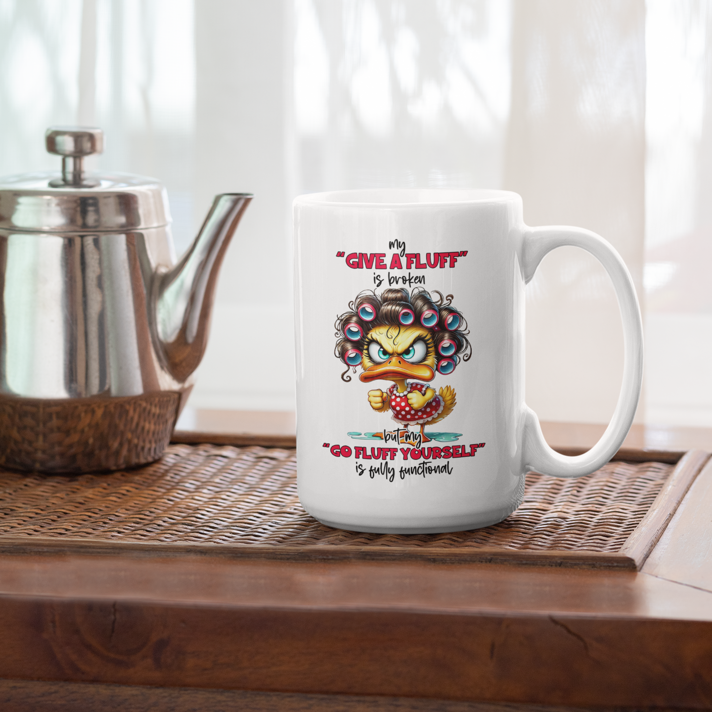 A white coffee mug  sitting on a wood table with a mad female duck saying my "give a fluff" is broken " go fluff yourself" is fully functional
