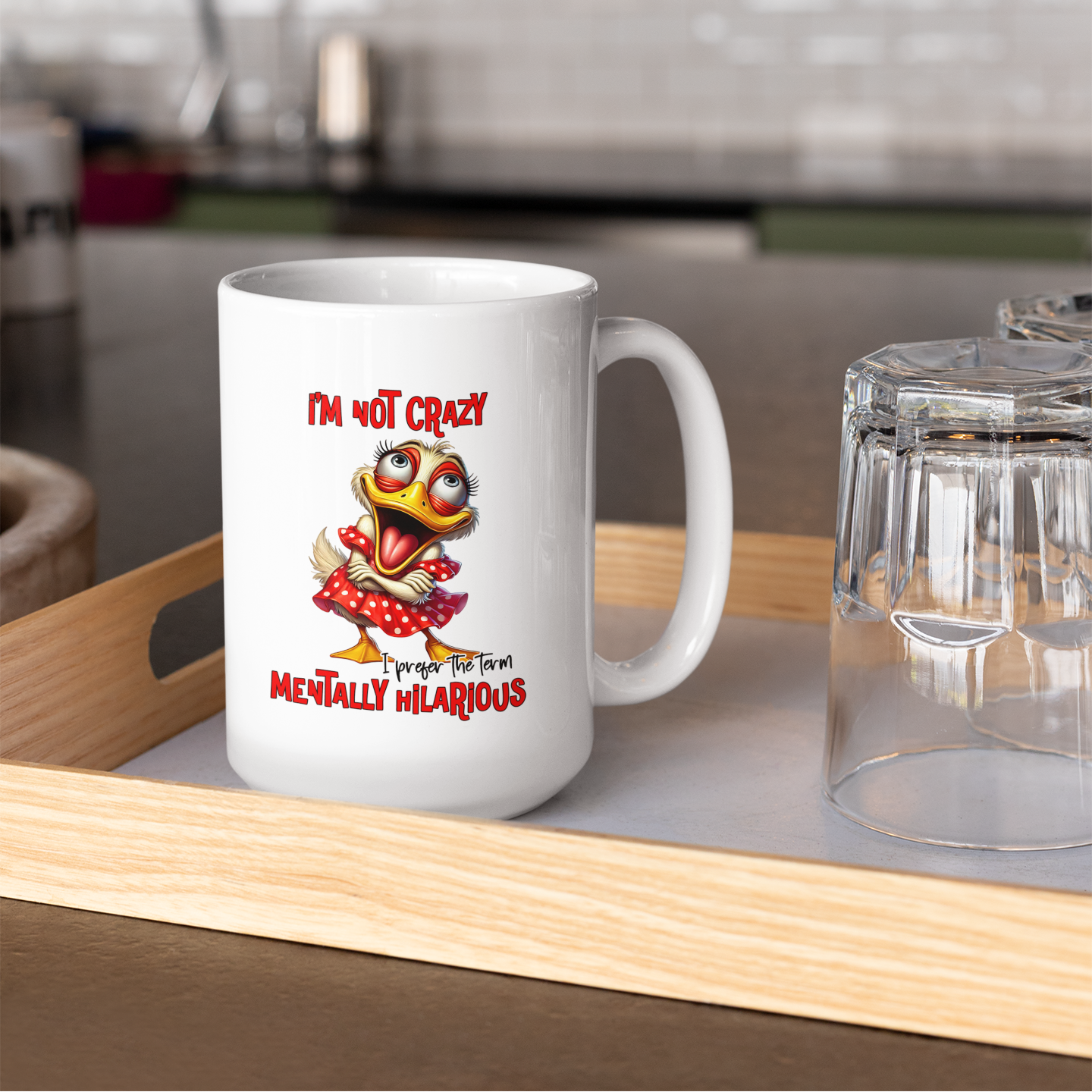 A white coffee mug sitting on a kitchen counter with a female cartoon duck crossing her arms and saying I'm not crazy I prefer the term mentally hilarious