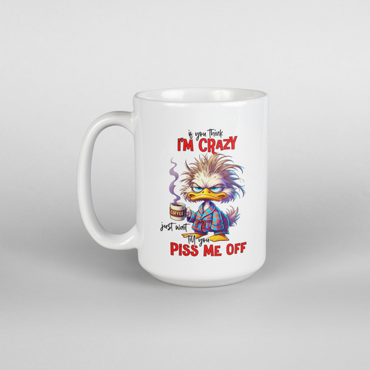 A white coffee mug with a cartoon male duck in pajamas holding a coffee mug and text that says i you think I'm crazy just wait till you piss me off