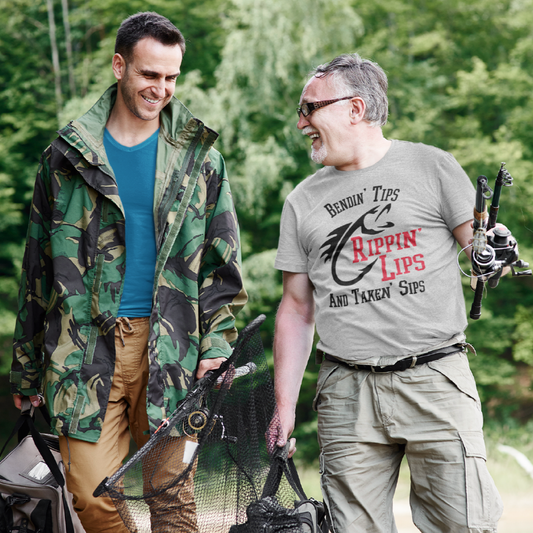two men walking with fishing gear laughing and one is wearing a grey t shirt with a fish and a quote that says Bendin' Tips Rippn' Lips and taken' sips